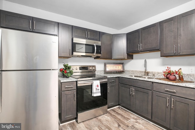 903 Bellows Ave, Fredericksburg, VA 22405 - kitchen featuring stainless steel appliances, a sink, light wood-style floors, light stone counters, and dark brown cabinetry