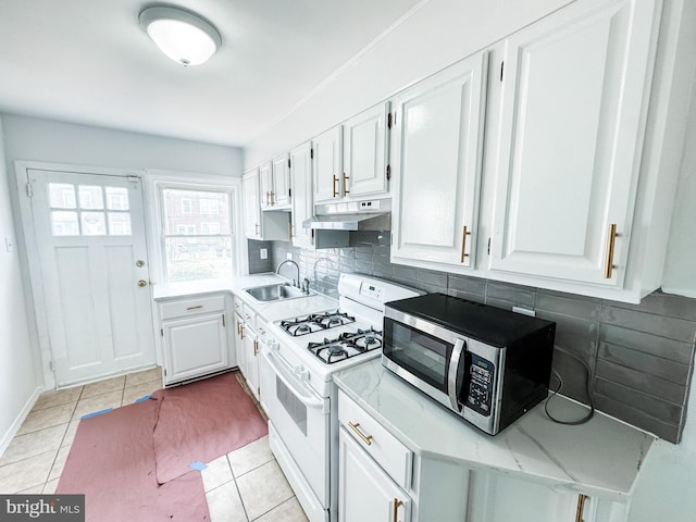 2714 N Pine St, Wilmington, DE 19802 - kitchen with white gas stove, stainless steel microwave, a sink, under cabinet range hood, and tasteful backsplash