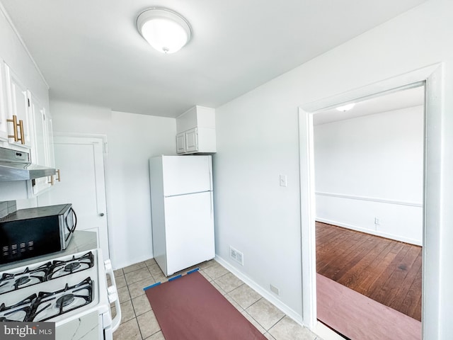 2714 N Pine St, Wilmington, DE 19802 - kitchen with white appliances, under cabinet range hood, white cabinets, baseboards, and light tile patterned flooring