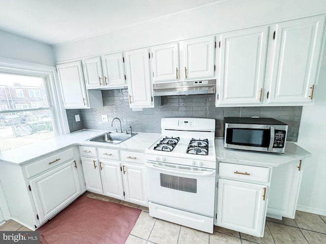 2714 N Pine St, Wilmington, DE 19802 - kitchen featuring white gas range, stainless steel microwave, under cabinet range hood, a sink, and tasteful backsplash