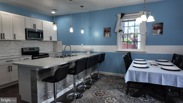 263B 3rd St, Hanover, PA 17331 - kitchen with stainless steel microwave, black electric range, a kitchen breakfast bar, tasteful backsplash, and a chandelier