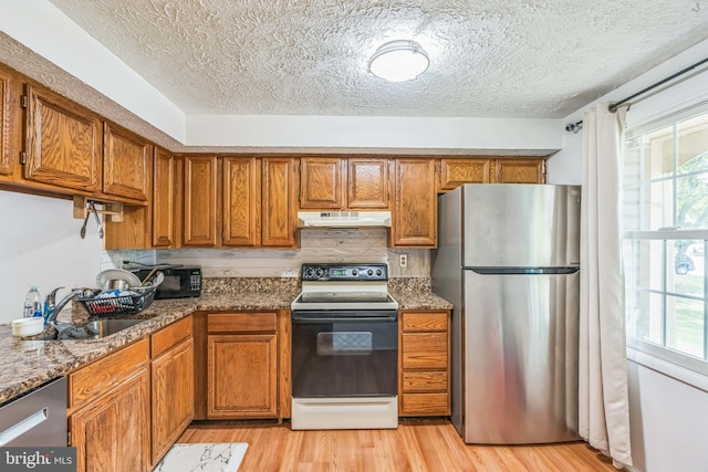 5959 Rowanberry Dr Unit 8E, Elkridge, MD 21075 - kitchen with appliances with stainless steel finishes, under cabinet range hood, a sink, brown cabinets, and a textured ceiling