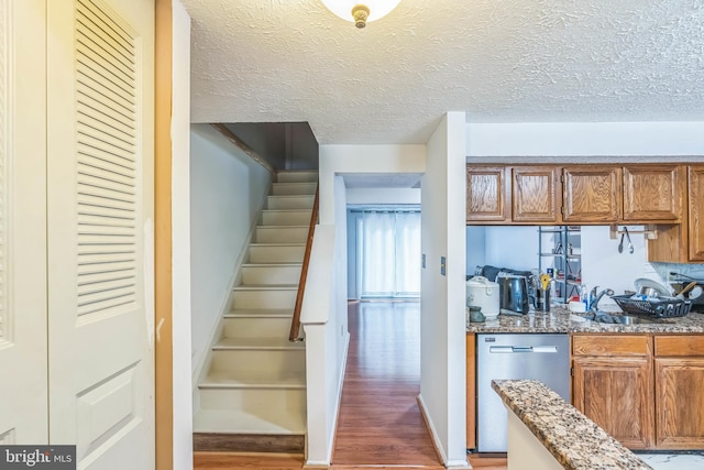 5959 Rowanberry Dr Unit 8E, Elkridge, MD 21075 - kitchen featuring dishwasher, light wood-style floors, brown cabinetry, light stone countertops, and a textured ceiling