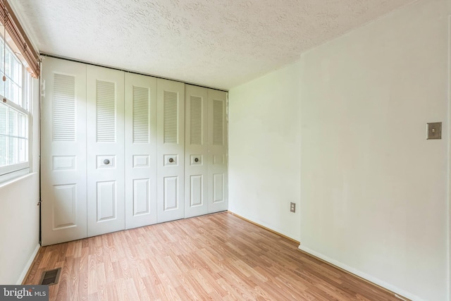 5959 Rowanberry Dr Unit 8E, Elkridge, MD 21075 - unfurnished bedroom featuring light wood finished floors, a closet, multiple windows, a textured ceiling, and baseboards