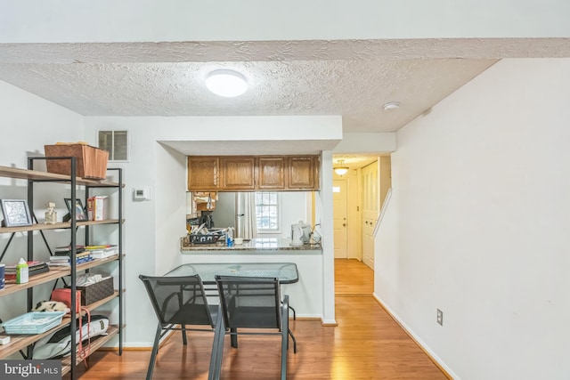 5959 Rowanberry Dr Unit 8E, Elkridge, MD 21075 - kitchen with light wood finished floors, brown cabinets, freestanding refrigerator, a textured ceiling, and baseboards