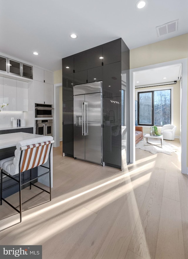 1573 Westmoreland St, Mclean, VA 22101 - kitchen with appliances with stainless steel finishes, dark cabinets, light wood-type flooring, recessed lighting, and modern cabinets