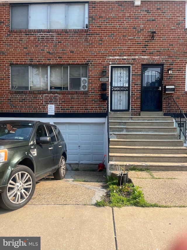 1231 W Champlost St, Philadelphia, PA 19141 - view of exterior entry featuring brick siding, an attached garage, and concrete driveway
