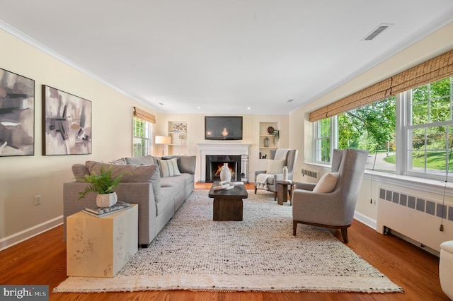 653 Broad Acres Rd, Penn Valley, PA 19072 - living room with radiator heating unit, a lit fireplace, baseboards, wood finished floors, and ornamental molding