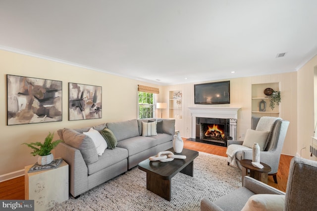 653 Broad Acres Rd, Penn Valley, PA 19072 - living room featuring wood finished floors, crown molding, a lit fireplace, baseboards, and built in features