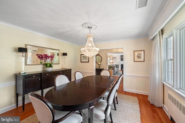653 Broad Acres Rd, Penn Valley, PA 19072 - dining area with radiator heating unit, wood finished floors, a chandelier, ornamental molding, and baseboards