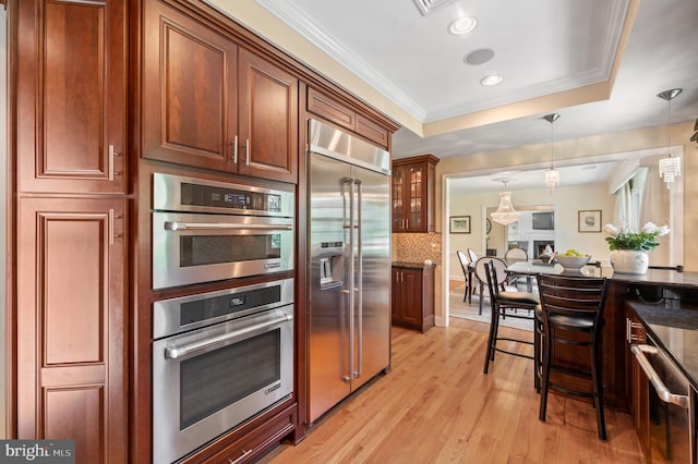 653 Broad Acres Rd, Penn Valley, PA 19072 - kitchen with appliances with stainless steel finishes, a tray ceiling, dark stone countertops, hanging light fixtures, and light wood finished floors