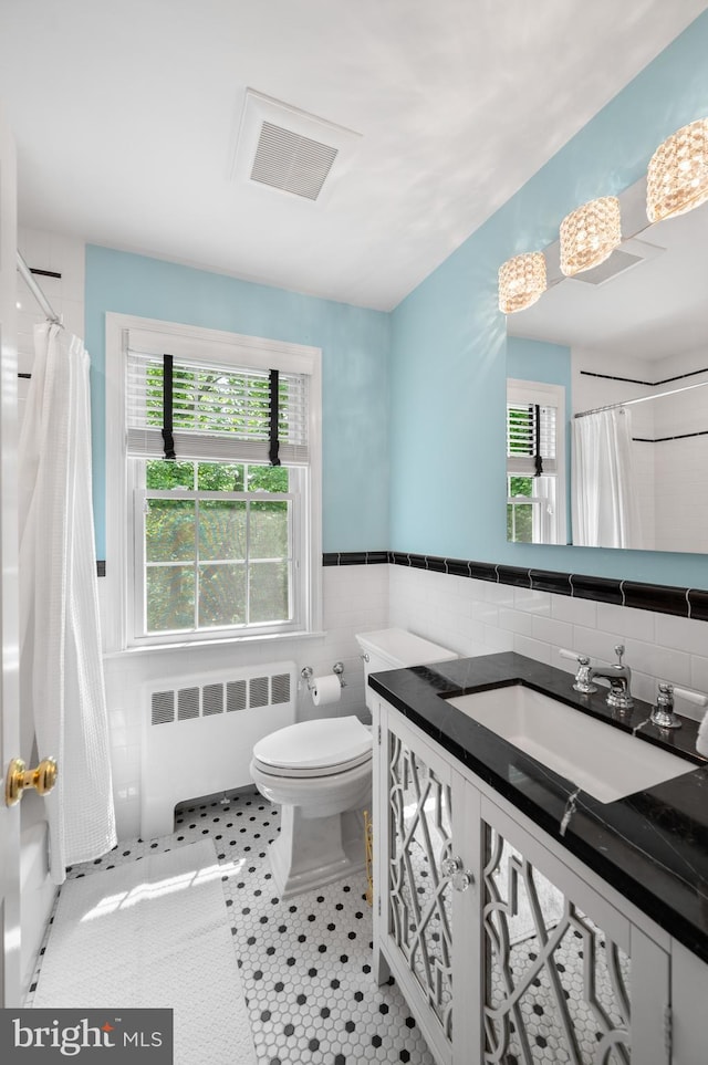 653 Broad Acres Rd, Penn Valley, PA 19072 - full bathroom with radiator, tile walls, vanity, toilet, and plenty of natural light