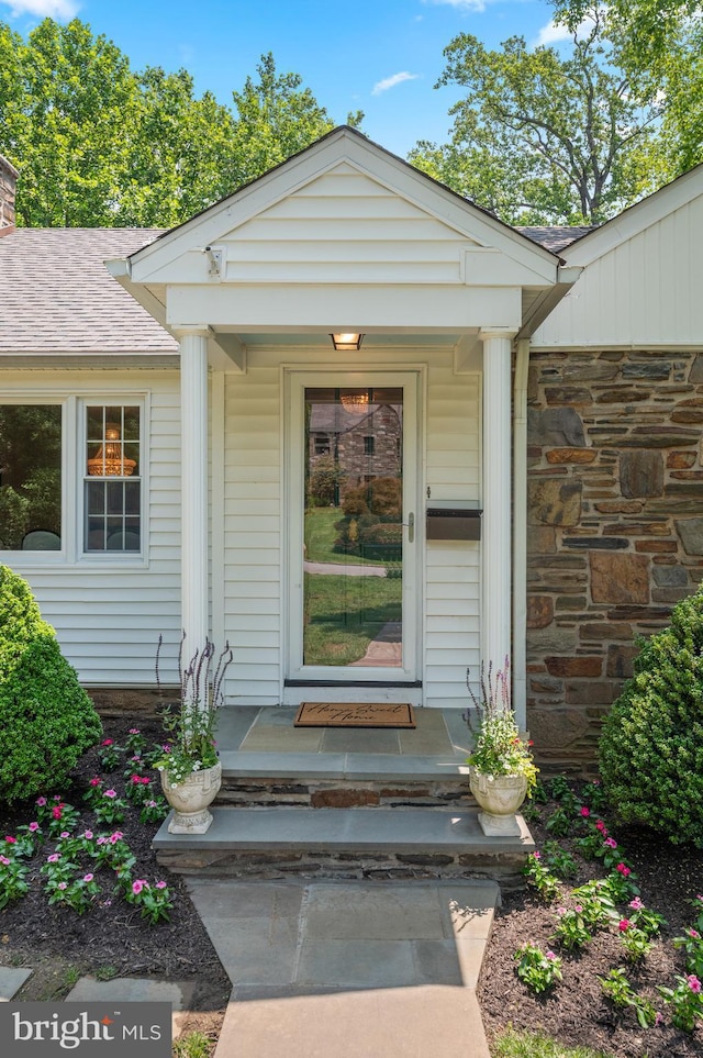 653 Broad Acres Rd, Penn Valley, PA 19072 - entrance to property featuring stone siding, roof with shingles, covered porch, and a chimney