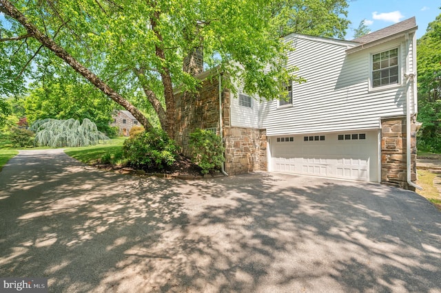 653 Broad Acres Rd, Penn Valley, PA 19072 - view of side of property with stone siding, asphalt driveway, and a garage