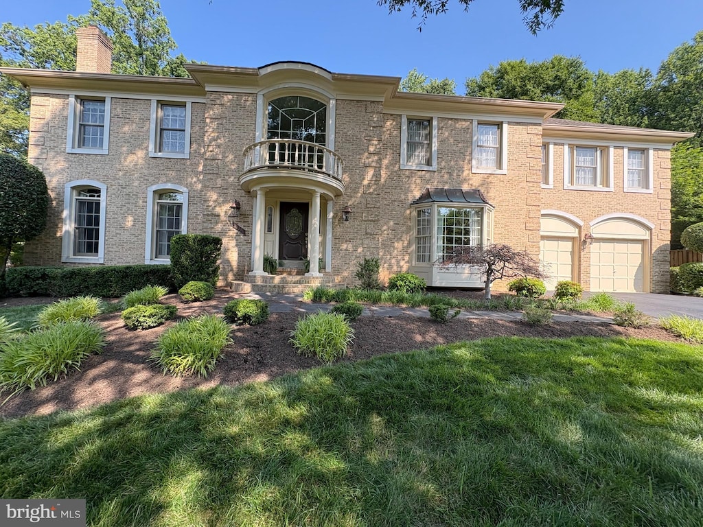 9111 Oak Chase Ct, Fairfax Station, VA 22039 - colonial house with a balcony, a chimney, driveway, a garage, and brick siding