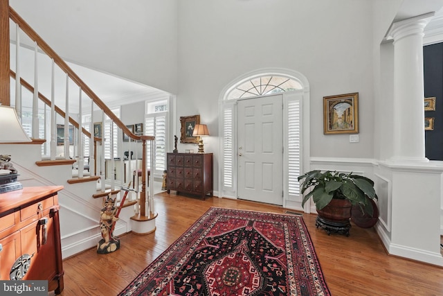 6321 Wilmington Dr, Burke, VA 22015 - foyer entrance featuring ornate columns, light wood-style flooring, a high ceiling, and stairs
