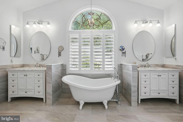 6321 Wilmington Dr, Burke, VA 22015 - bathroom featuring tile walls, healthy amount of natural light, lofted ceiling, two vanities, and a freestanding tub