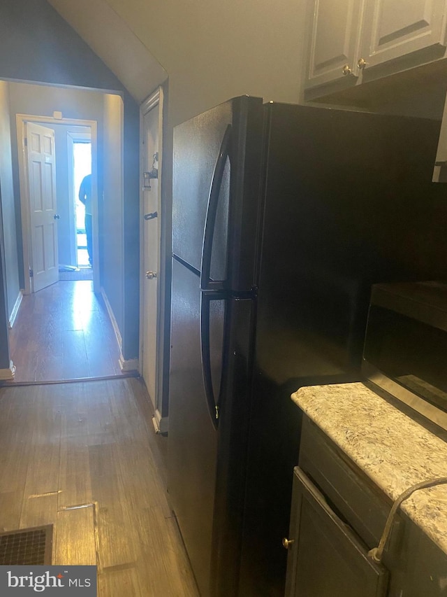 2919 Baker St, Baltimore, MD 21216 - kitchen with stainless steel microwave, light wood-type flooring, baseboards, freestanding refrigerator, and white cabinetry