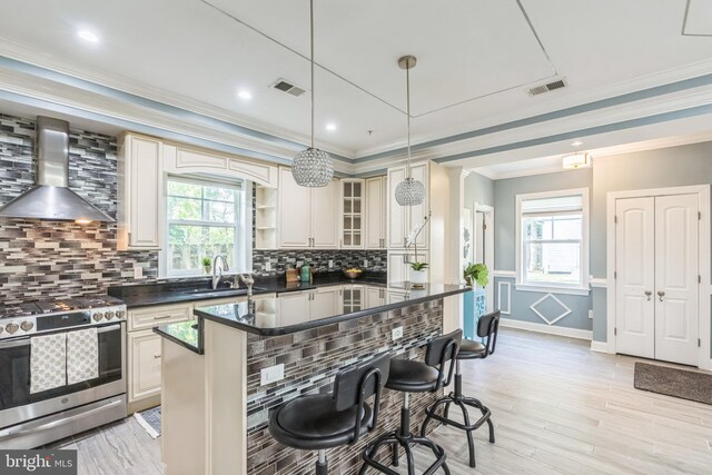 3112 Lancer Dr, Hyattsville, MD 20782 - kitchen with gas stove, wall chimney range hood, a breakfast bar, dark countertops, and ornamental molding