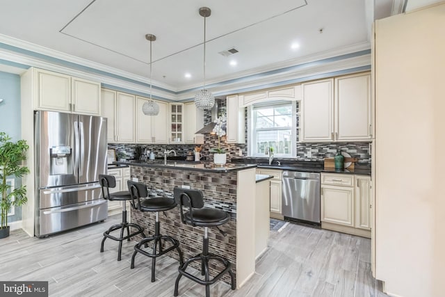 3112 Lancer Dr, Hyattsville, MD 20782 - kitchen featuring stainless steel appliances, dark countertops, cream cabinetry, a breakfast bar, and light wood-style flooring