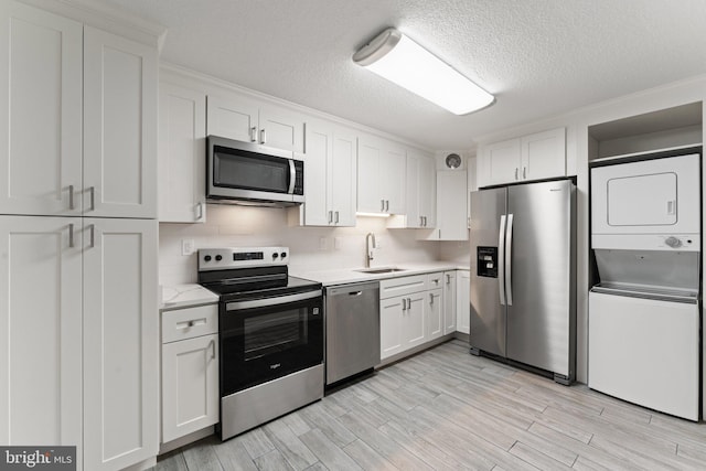 203 Yoakum Pkwy Unit 603, Alexandria, VA 22304 - kitchen with appliances with stainless steel finishes, stacked washer / drying machine, a sink, light countertops, and white cabinets