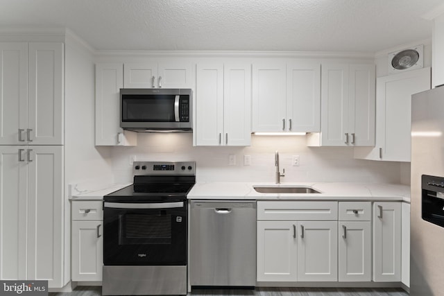 203 Yoakum Pkwy Unit 603, Alexandria, VA 22304 - kitchen featuring appliances with stainless steel finishes, a sink, white cabinetry, a textured ceiling, and decorative backsplash