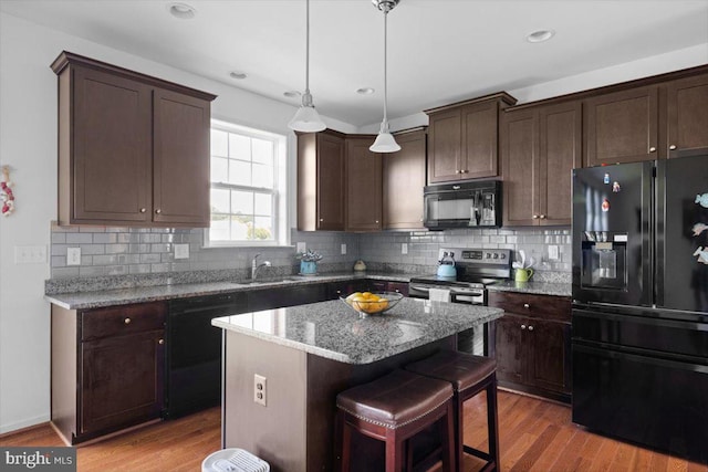 100 Taylor Ct, Stephenson, VA 22656 - kitchen with black appliances, dark brown cabinetry, a kitchen bar, stone counters, and a center island