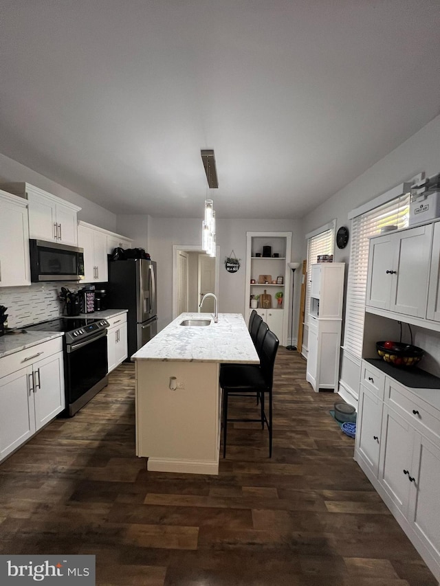 713 Juniper St, Quakertown, PA 18951 - kitchen with appliances with stainless steel finishes, a sink, white cabinets, an island with sink, and backsplash