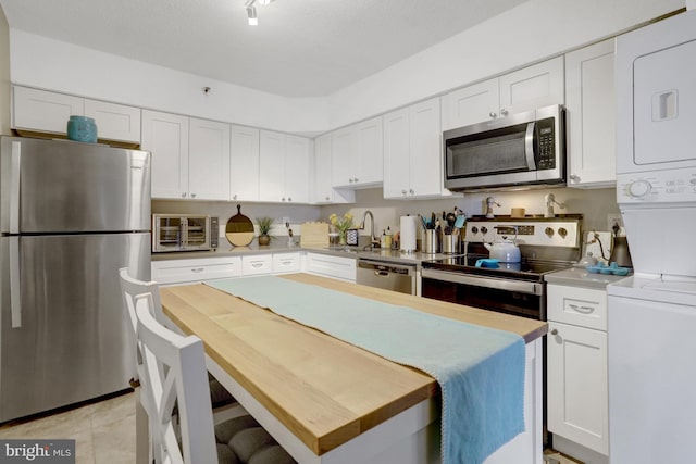 3713 S George Mason Dr Unit 713, Falls Church, VA 22041 - kitchen featuring appliances with stainless steel finishes, estacked washer and dryer, a sink, and white cabinetry