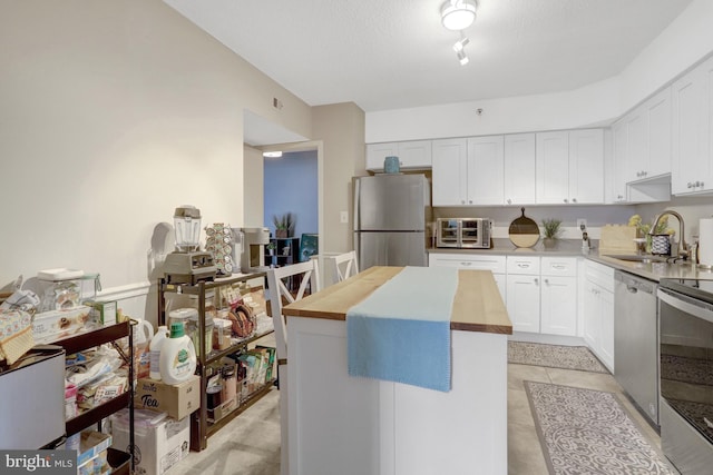3713 S George Mason Dr Unit 713, Falls Church, VA 22041 - kitchen featuring appliances with stainless steel finishes, a sink, butcher block counters, a center island, and white cabinets