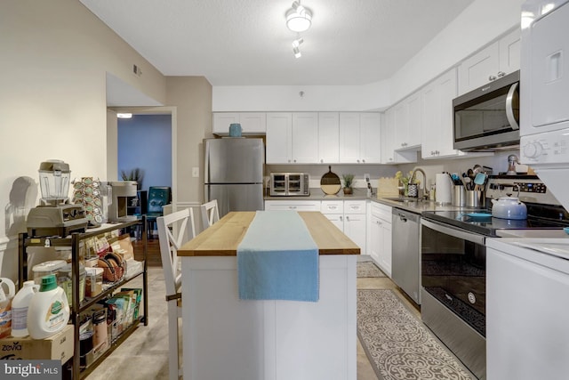 3713 S George Mason Dr Unit 713, Falls Church, VA 22041 - kitchen featuring stainless steel appliances, wood counters, a sink, white cabinets, and a center island