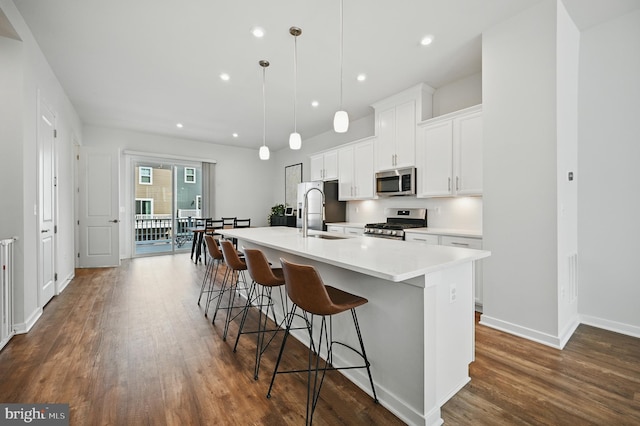 1763 Hickory Woods Rd, Dumfries, VA 22026 - kitchen featuring stainless steel appliances, dark wood-style flooring, an island with sink, a breakfast bar, and white cabinetry