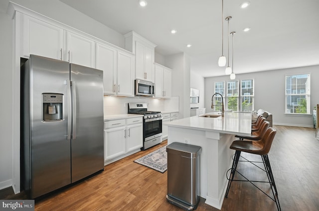 1763 Hickory Woods Rd, Dumfries, VA 22026 - kitchen with appliances with stainless steel finishes, wood finished floors, white cabinets, a kitchen island with sink, and light countertops