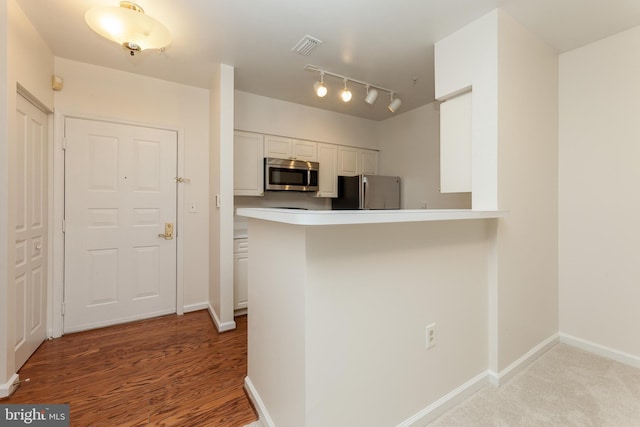 2204 Westcourt Ln Unit 201, Herndon, VA 20170 - kitchen with appliances with stainless steel finishes, white cabinets, a peninsula, light countertops, and wood finished floors