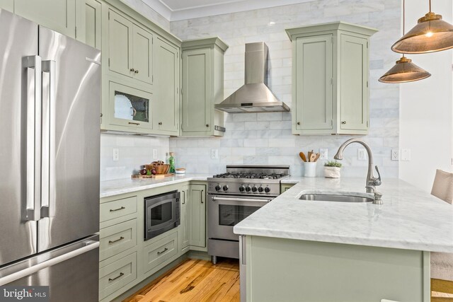 1235 S St NW Unit 1, Washington, DC 20009 - kitchen with stainless steel appliances, wall chimney range hood, green cabinetry, a sink, and a peninsula