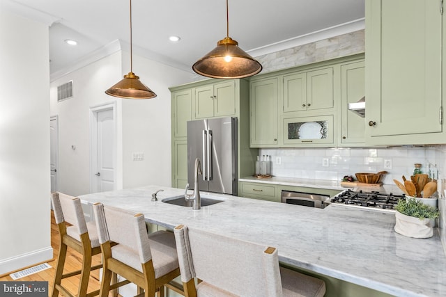 1235 S St NW Unit 1, Washington, DC 20009 - kitchen with green cabinetry, a sink, stainless steel appliances, a breakfast bar, and ornamental molding