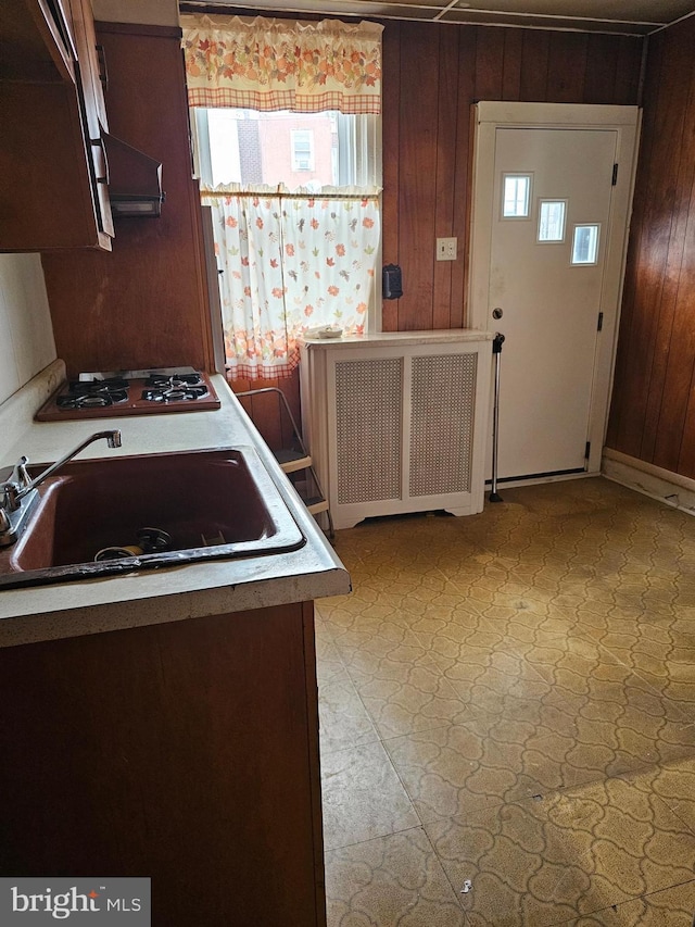 1943 W Sparks St, Philadelphia, PA 19141 - kitchen with radiator heating unit, a sink, wood walls, light flooring, and gas stovetop