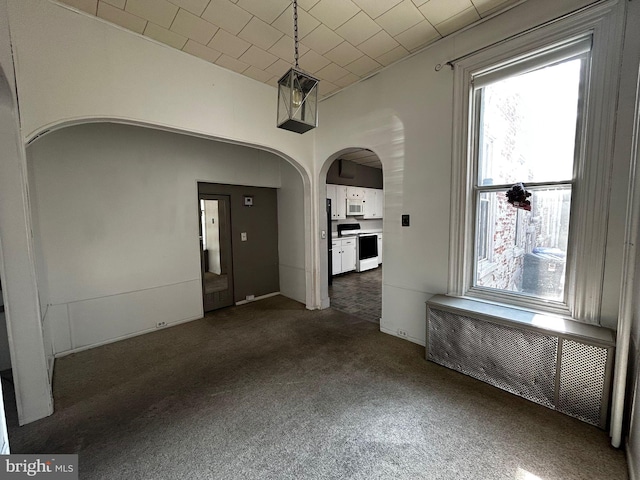 342 S 4th St, Reading, PA 19602 - unfurnished dining area featuring radiator, arched walkways, and dark colored carpet