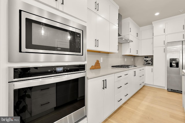7458 Backett Wood Ter Unit 401, Mclean, VA 22102 - kitchen featuring appliances with stainless steel finishes, wall chimney range hood, light countertops, light wood-style flooring, and recessed lighting
