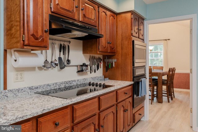 1492 Cumberland Dr, Rockingham, VA 22801 - kitchen with under cabinet range hood, black appliances, brown cabinets, light wood-style flooring, and baseboards