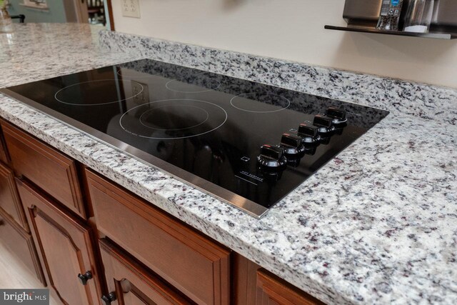 1492 Cumberland Dr, Rockingham, VA 22801 - kitchen view of black electric stovetop, brown cabinetry, and light stone counters