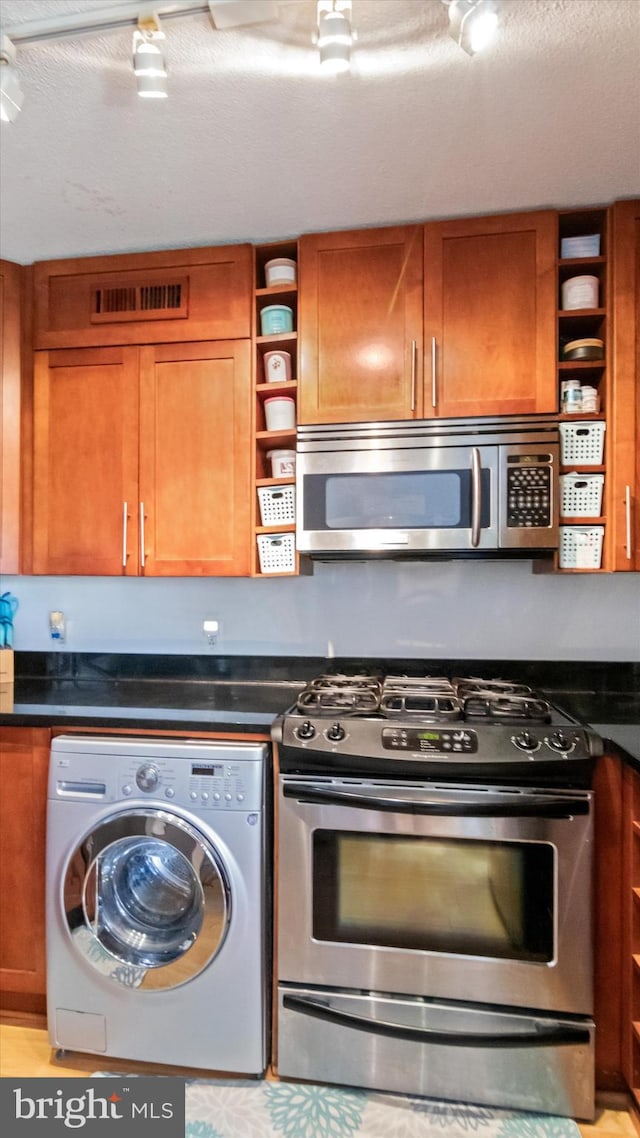 7333 New Hampshire Ave Unit 800, Takoma Park, MD 20912 - kitchen featuring washer / clothes dryer, stainless steel appliances, open shelves, brown cabinetry, and dark countertops