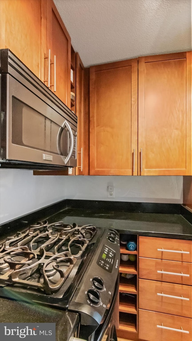 7333 New Hampshire Ave Unit 800, Takoma Park, MD 20912 - kitchen view of stainless steel microwave, gas range oven, dark countertops, a textured ceiling, and brown cabinets