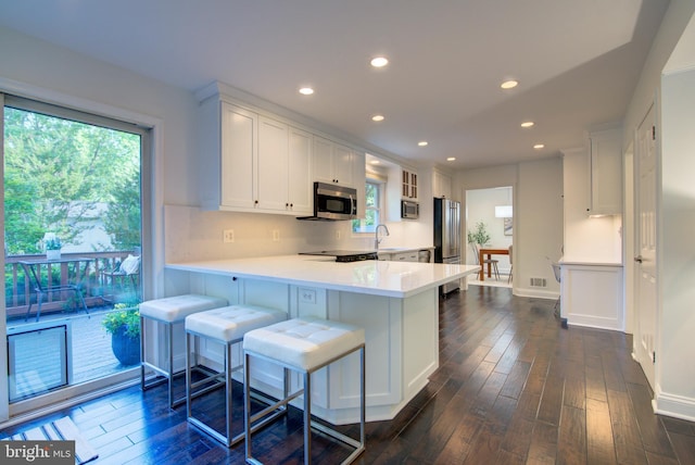 12013 Cheviot Dr, Herndon, VA 20170 - kitchen featuring appliances with stainless steel finishes, dark wood-style flooring, light countertops, white cabinets, and a peninsula