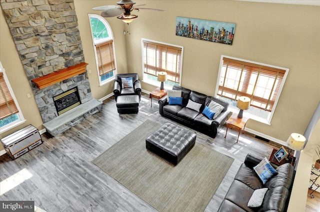 17 N Carolina Ave, Reading, PA 19608 - living room featuring a ceiling fan, wood finished floors, a stone fireplace, baseboards, and a high ceiling