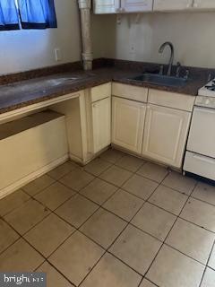 14 3rd Ave, Baltimore, MD 21225 - kitchen with a sink, light tile patterned floors, white range with gas stovetop, dark countertops, and healthy amount of natural light