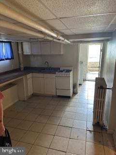14 3rd Ave, Baltimore, MD 21225 - kitchen featuring white range with gas stovetop, a sink, light tile patterned floors, and dark countertops