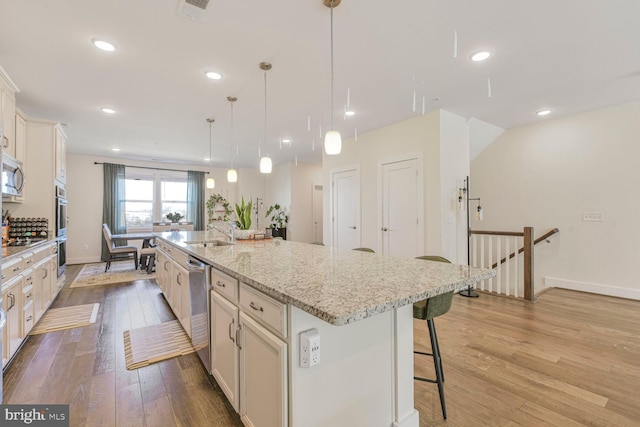 44878 Tiverton Sq, Ashburn, VA 20147 - kitchen with a sink, a kitchen bar, light wood-style flooring, stainless steel appliances, and a spacious island