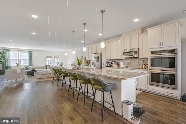 44878 Tiverton Sq, Ashburn, VA 20147 - kitchen featuring appliances with stainless steel finishes, a kitchen breakfast bar, dark wood finished floors, a spacious island, and light stone countertops