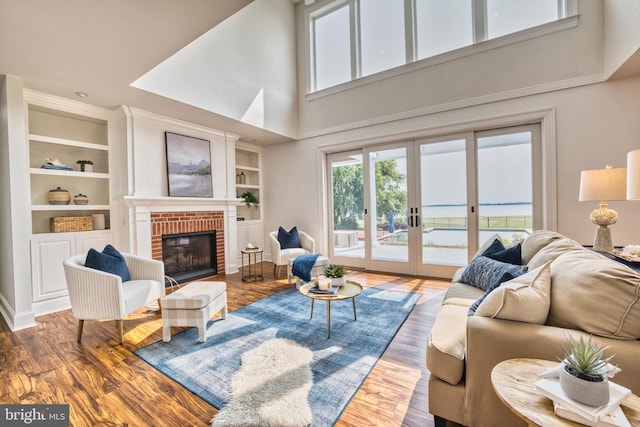 6153 Long Point Rd, Neavitt, MD 21652 - living room with a towering ceiling, french doors, a brick fireplace, built in features, and wood finished floors
